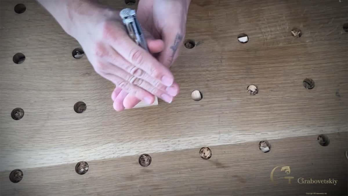 A hand cups the small rosette, a punch pinched between two fingers