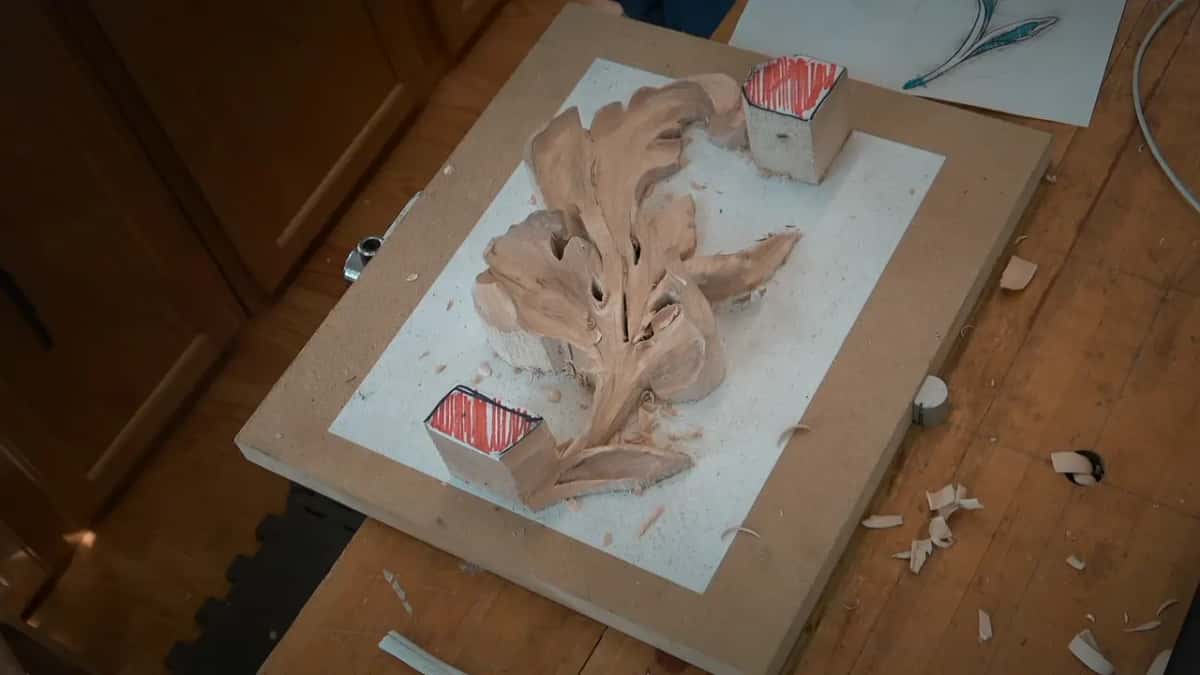 The whole carved leaf lying on white paper, red-topped blocks at both ends