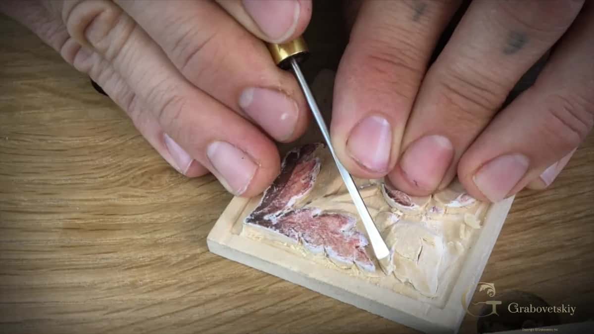 After the paper, the brass micro tool works the bare wood beside a leaf that still wears its print