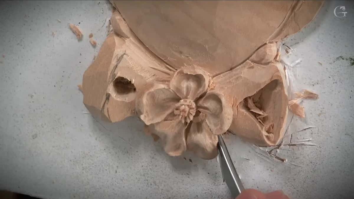 Two loops of the bow opened beside the small flower, torn fibers still sitting inside the right one