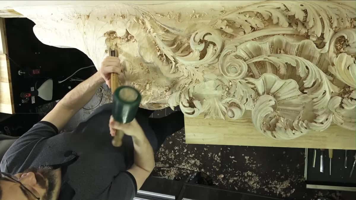 A green rubber mallet drives a gouge up into the big carving above my head