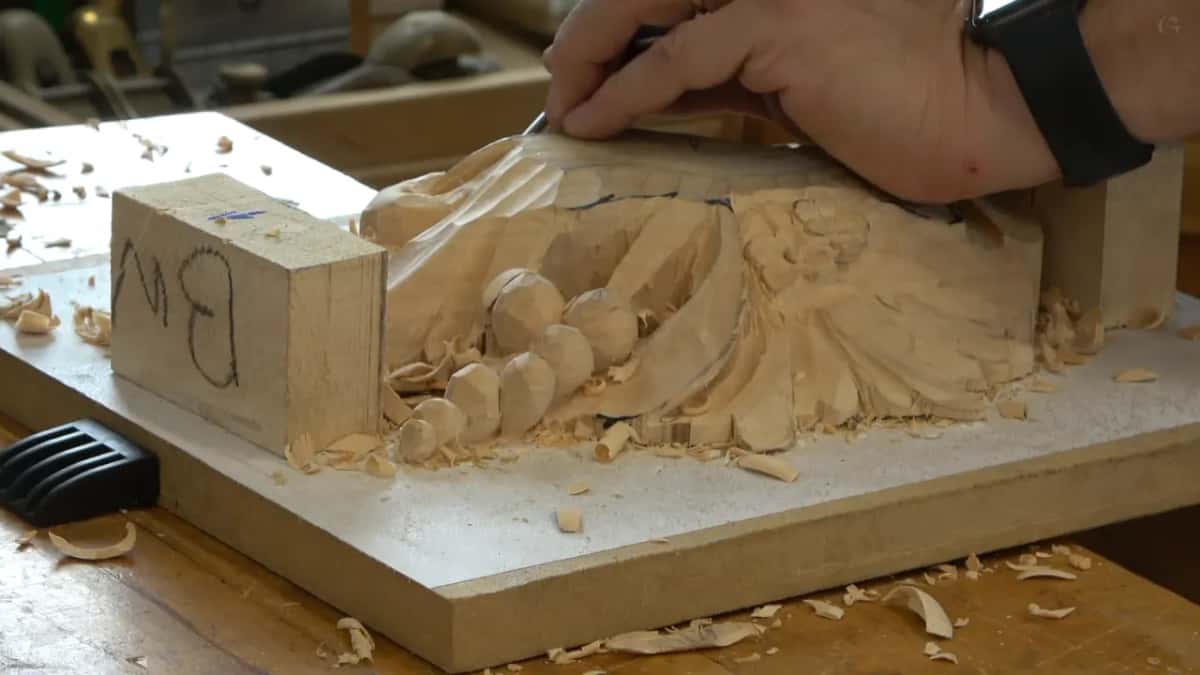 Low view along the bench while one hand works a small tool across the top edge of the lower layer