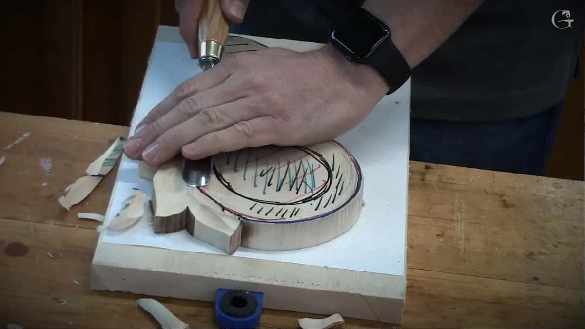 The second hand lies flat on the blade while the gouge enters a Byzantine leaf blank, chips nearby