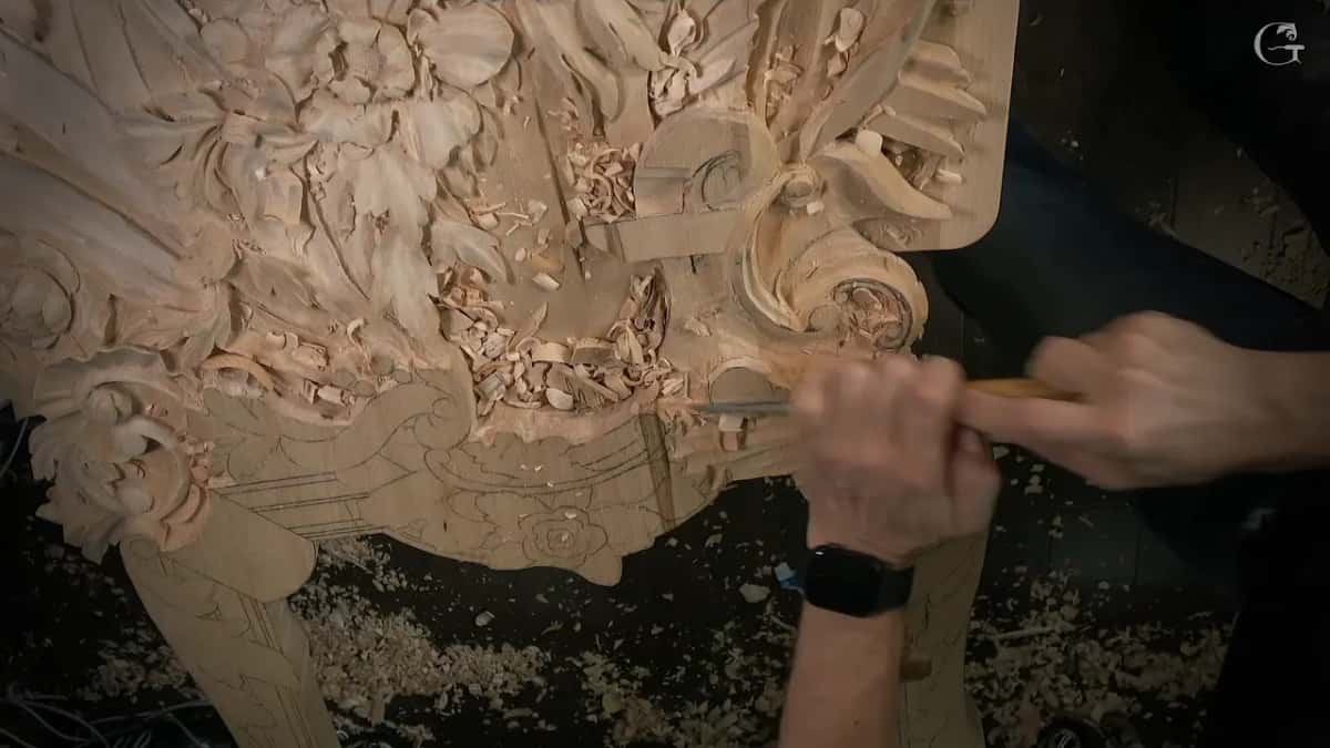Hands at the lower edge with a gouge aimed into the scroll