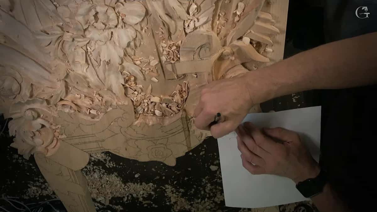 Paper drawing held flat on the lower edge of the panel while the other hand marks it