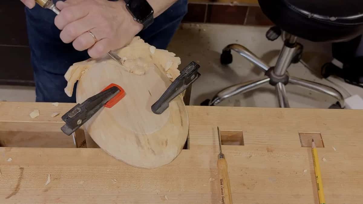 A fist wraps the handle while the edge works the grapes at the leaf end, with a spare tool lying on the bench