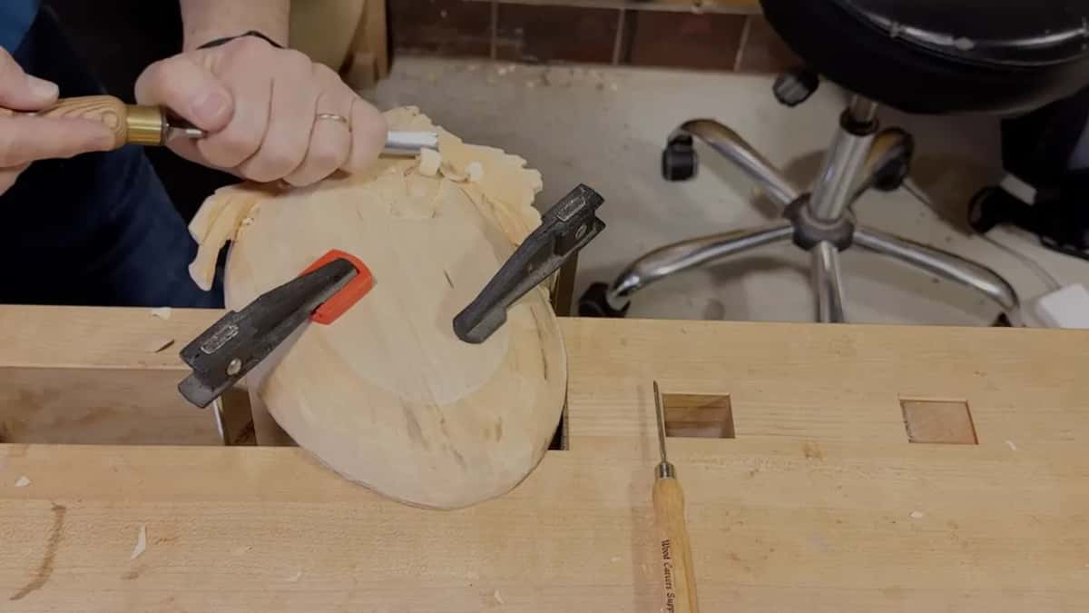 Both hands guide a small gold-ferrule tool into the grapes, with tiny chips beside them