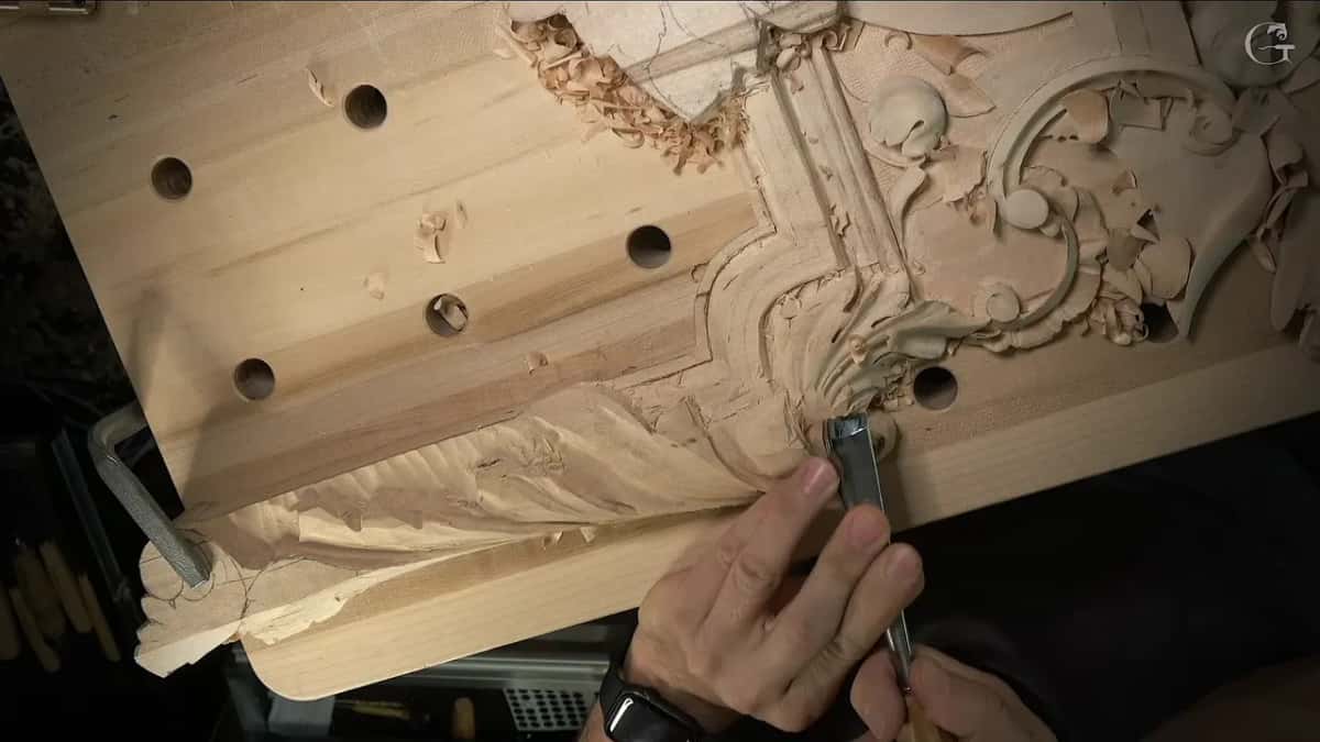 From overhead the leaf meets the volute and one hand holds a tool against it