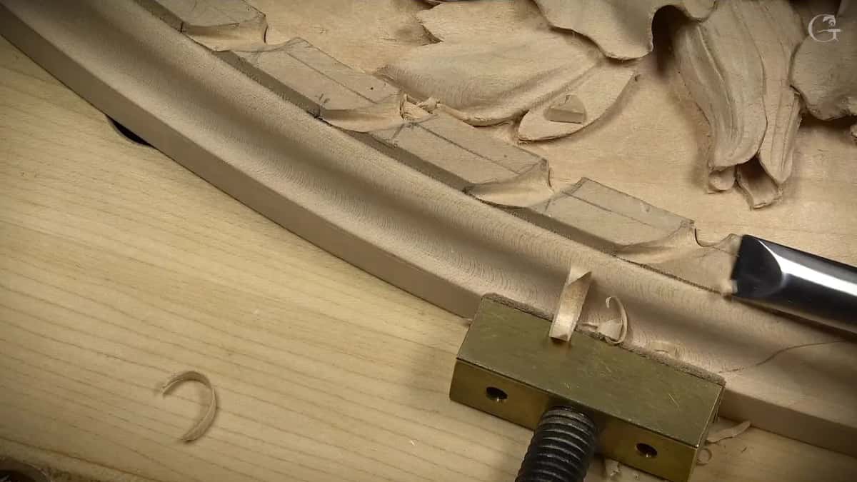 A flat gouge lowers the outer edge of the rim beside a brass clamp