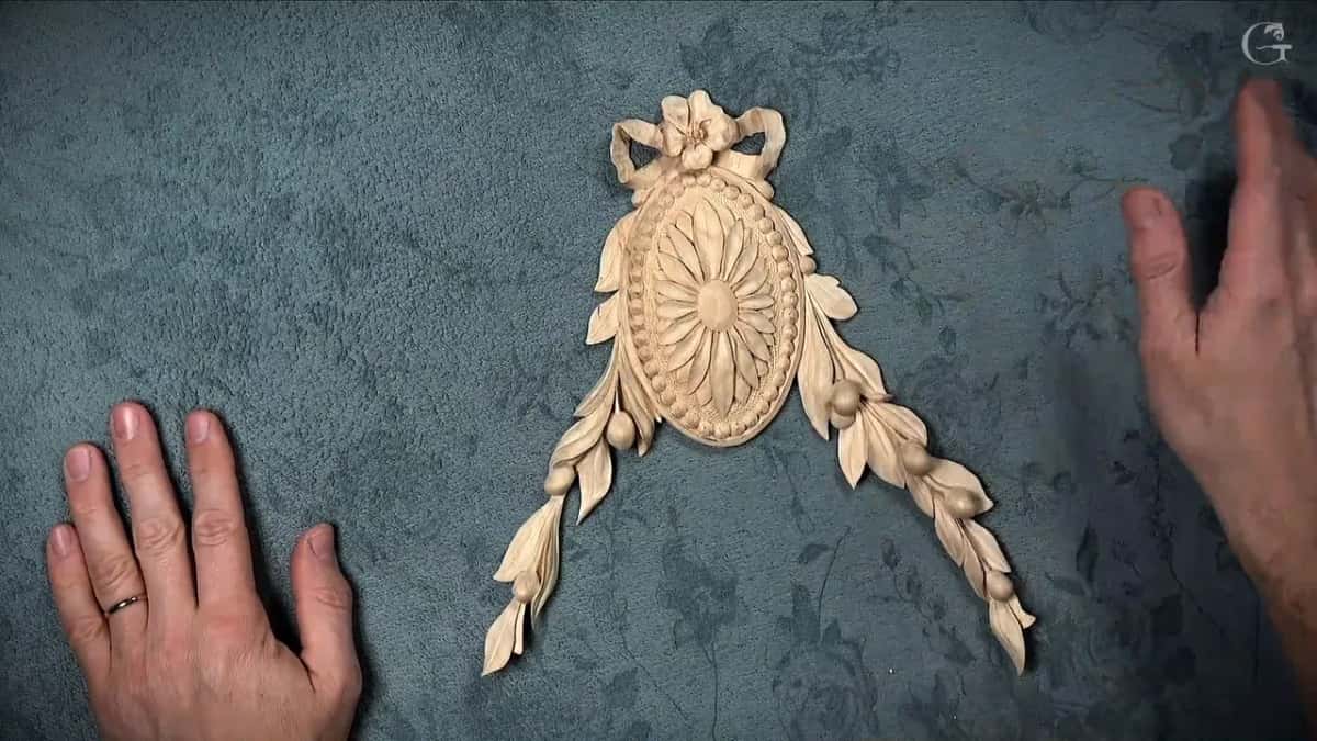 The finished rosette on a dark blue cloth, a hand resting at each side