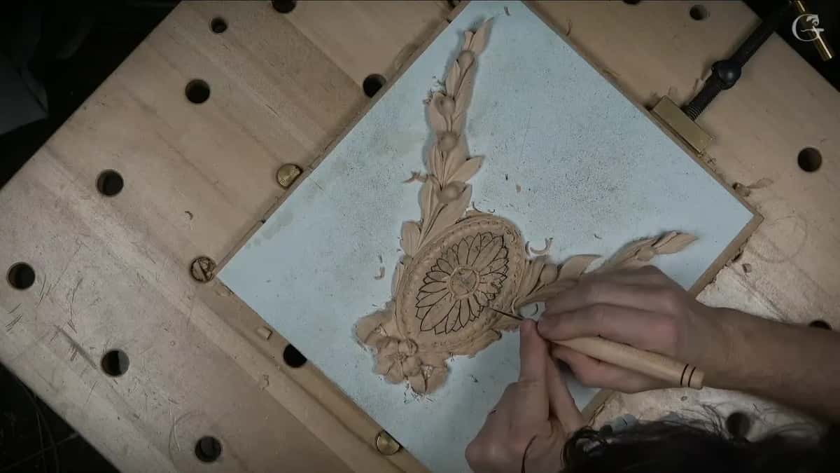 A pale handled knife at the edge of the drawn petals, guided by the fingers of the other hand