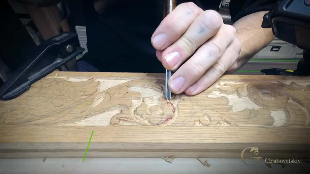 Working around the ring of a carved flower with a narrow gouge, colored marks still on the board