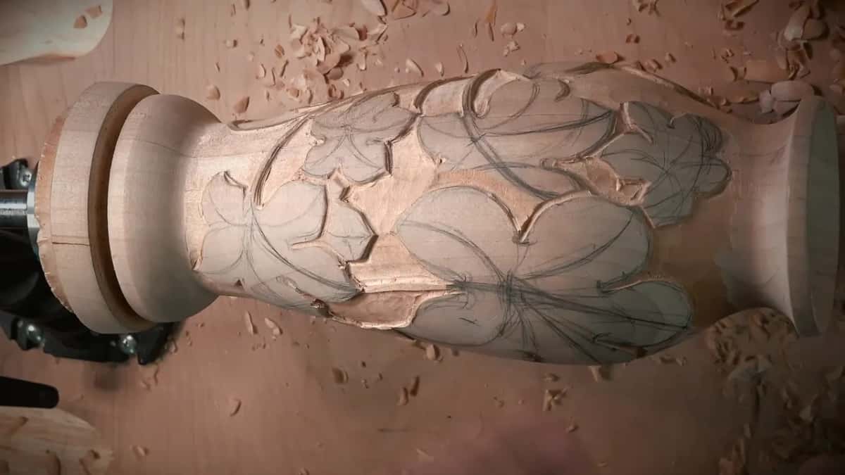 Turned vase held in the vise with its background lowered and every grape leaf still outlined in pencil