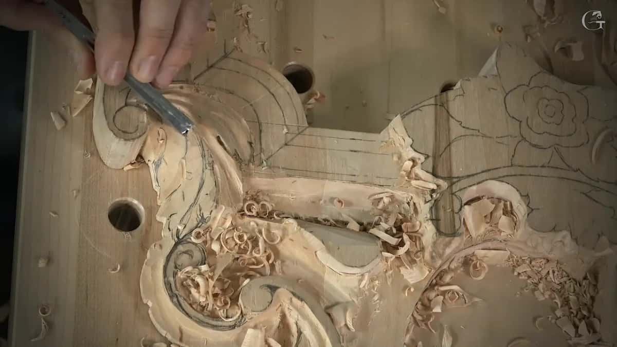 A narrow gouge in one hand fans fresh grooves across the lobes of an acanthus leaf